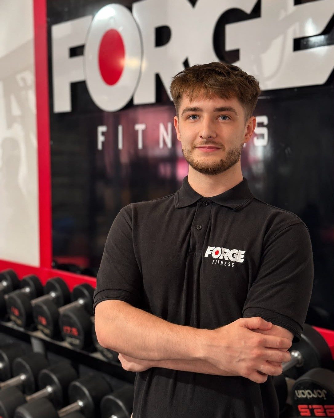A Forge coach in branded kit standing in front of the FORGE sign